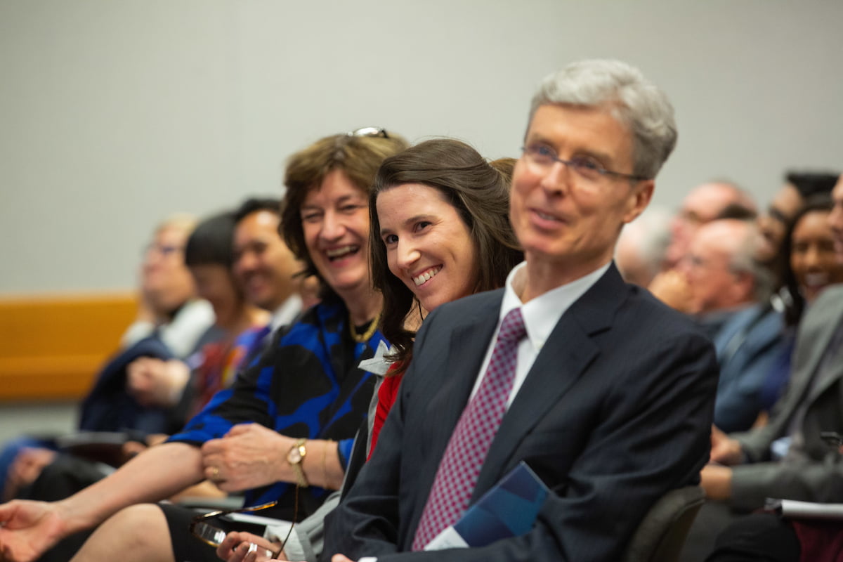 WeirFoulds Associate Kayla Theeuwen and Partner Greg Richards smile as Frank Walwyn speaks to audience